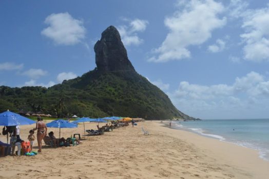 guarda sol na praia da conceicao com morro do pico noronha